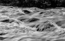 a black and white image of a rushing river